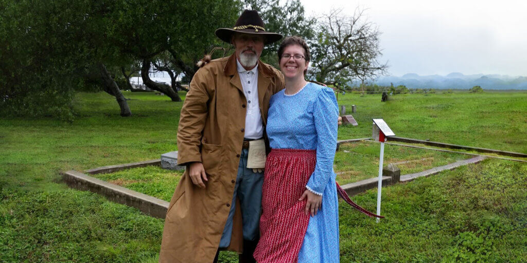 couple wearing pioneer clothing in field