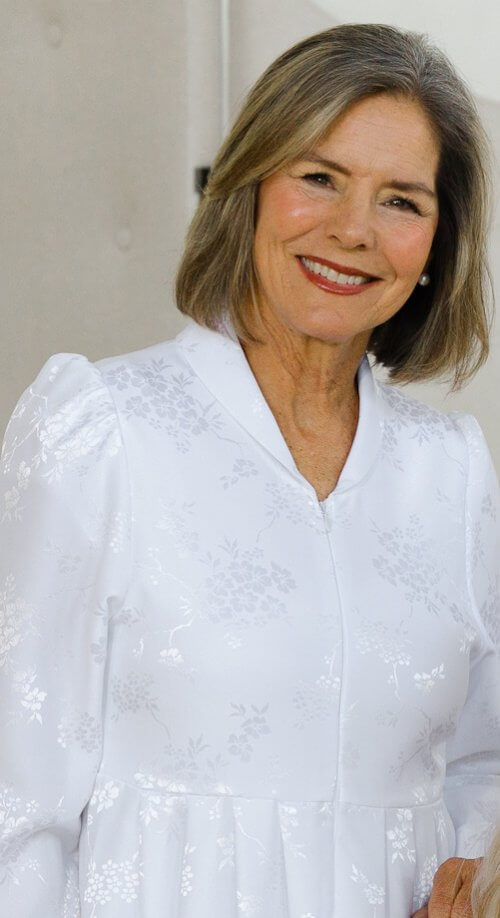 Nagoya Dress – White LDS Temple dress with a floral jacquard pattern, front zipper, pleated waist, and long sleeves.